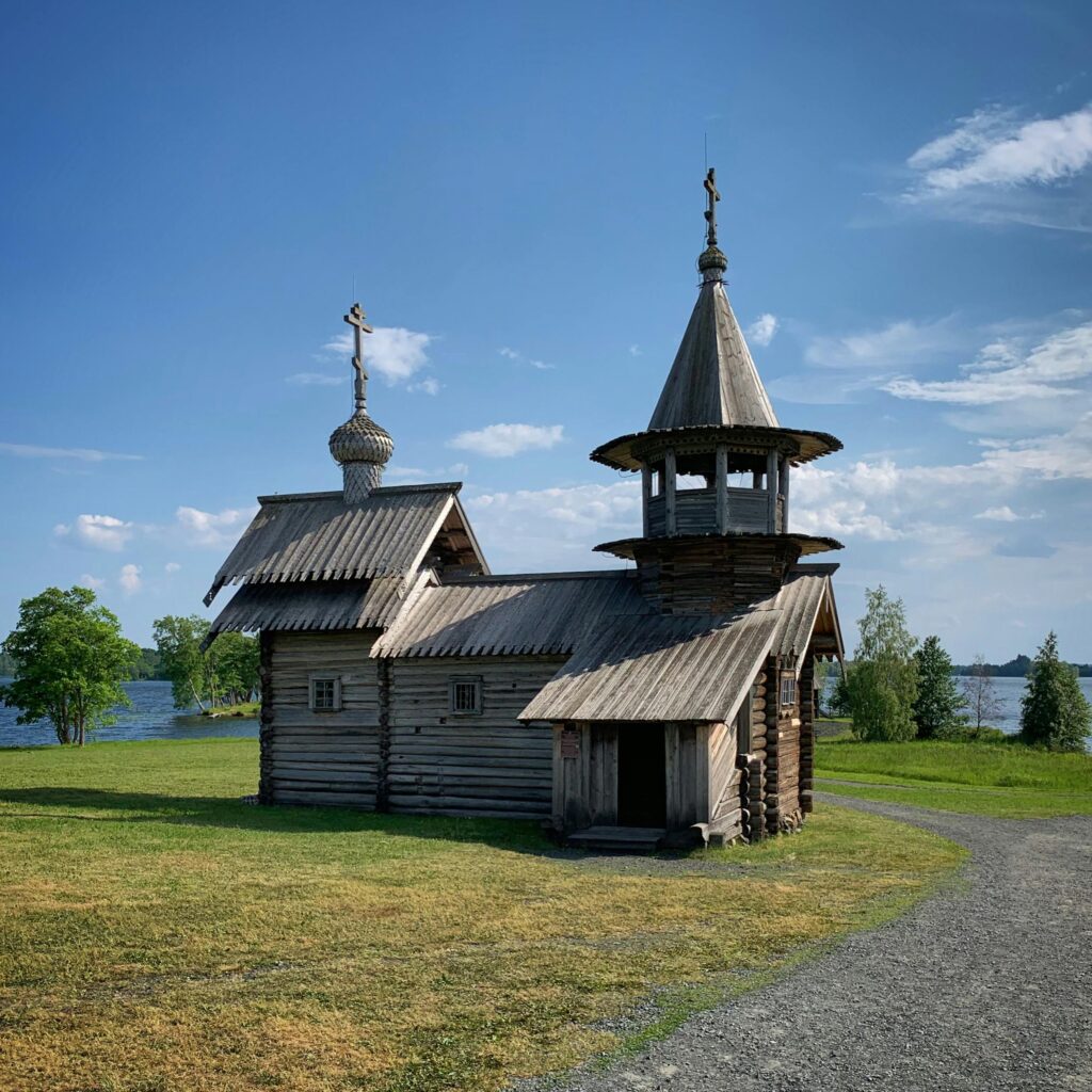 Charming wooden church by a lake in Karelia, Russia, under a clear summer sky.